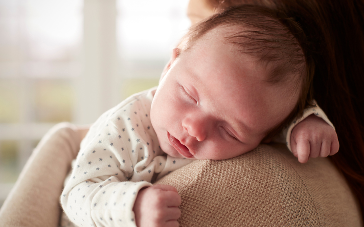 Parent holding newborn while sleeping.